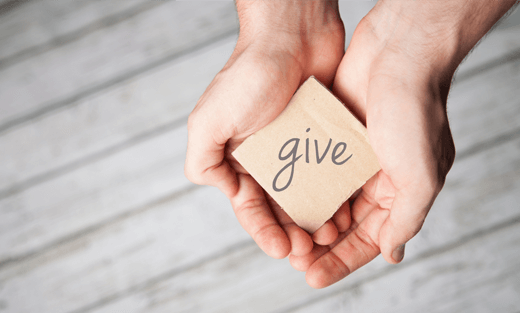 Two hands holding a square with give written on it.